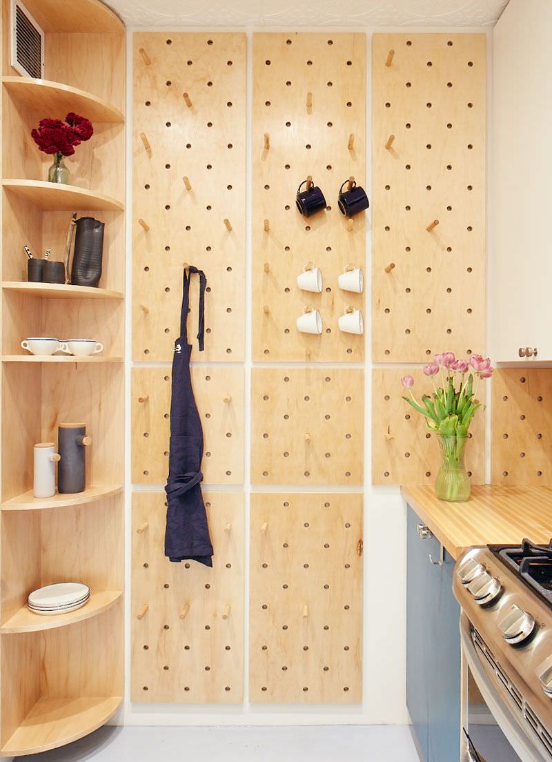 دکوراسیون آشپزخانه کوچک که برای چیدمان دکوریجات و وسائل تزئینی، روی دیوار آن قفسه کنجی و پگ بورد نصب شده است